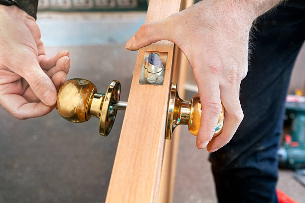door installation, worker installs door knob, woodworker hands close up.
